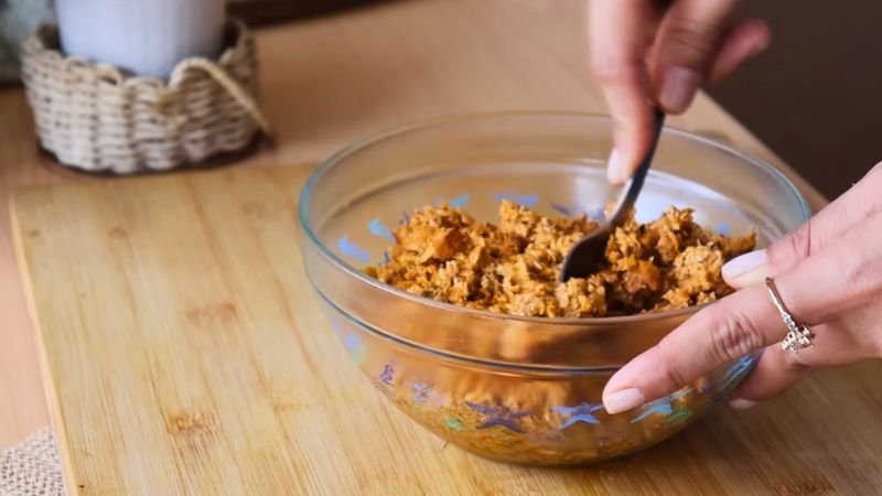 Relleno de pollo desmechado con sofrito de vegetales y pasta de tomate en un bol de vidrio para empanadas de auyama.