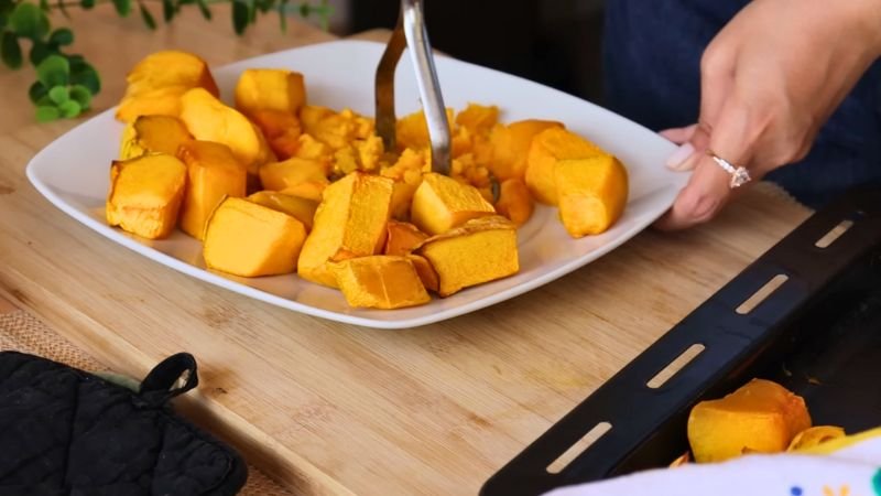 Persona triturando trozos de auyama (calabaza) cocida sobre un plato blanco para preparar la masa de las empanadas saludables.