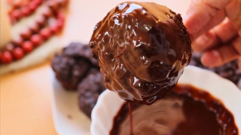 cobertura-chocolate-cupcakes-saludables.jpg Sumergiendo un cupcake saludable de avena y chocolate en una cobertura brillante de cacao amargo.
