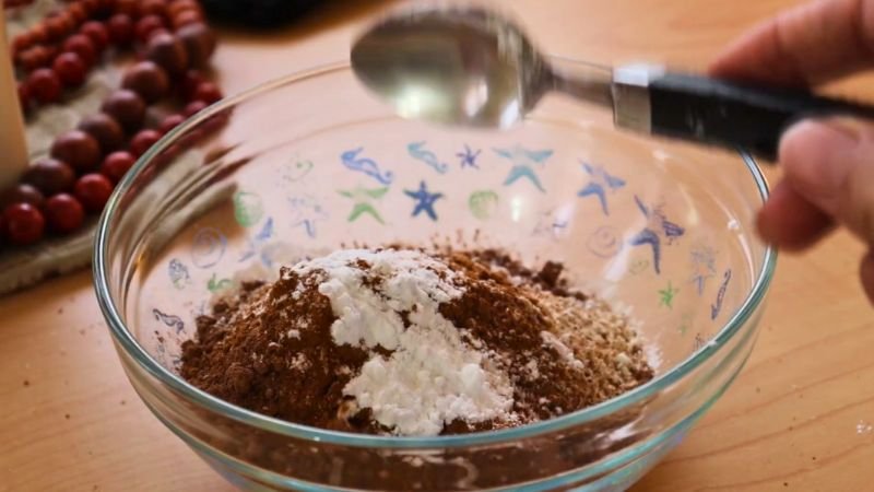 ingredientes-secos-cupcakes-saludables-avena-chocolate.jpg Mezcla de ingredientes secos para cupcakes saludables de avena y chocolate en un bol de vidrio.