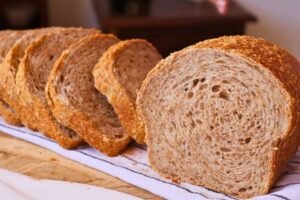 Rebanadas de pan integral de masa madre fácil y crujiente con miga esponjosa sobre un paño de cocina.