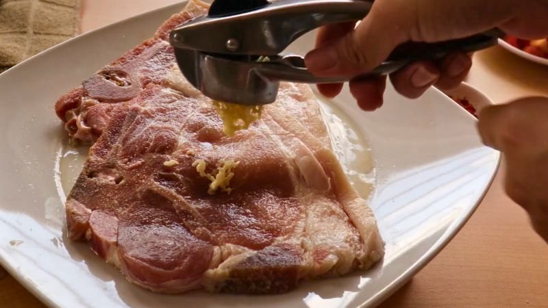 Paso 1: Sellar la proteína con ajo. Aderezando chuletas de cerdo con ajo fresco para la receta de sopa de lentejas rojas con pasta de Coffee María.