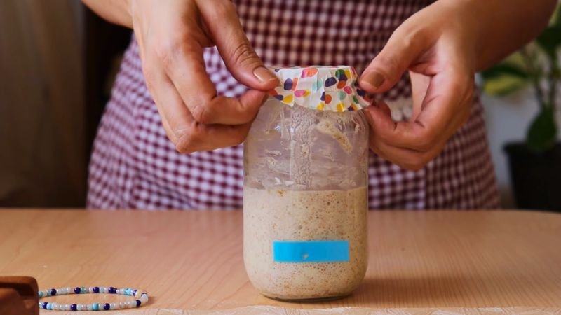 Primer plano del interior del frasco en el día 4, mostrando burbujas activas y la mezcla de 120g de harina con 60g de agua.