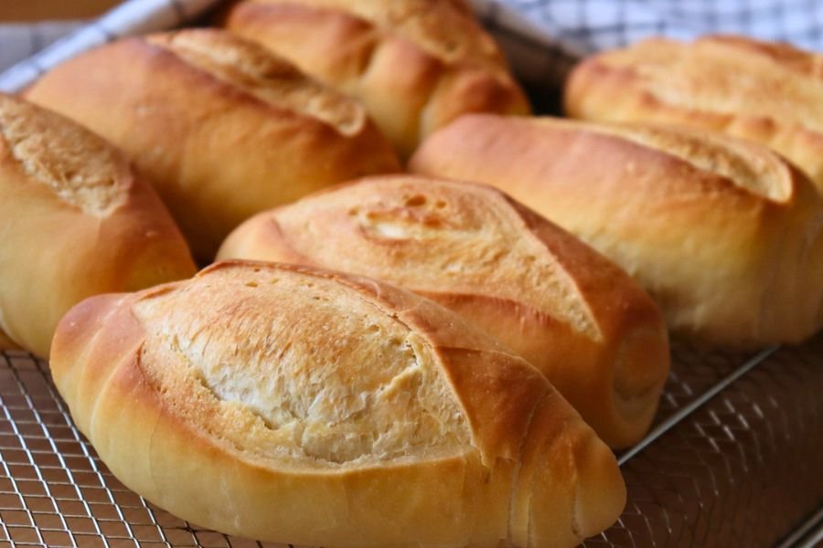 Pan francés con masa madre recién horneados sobre una rejilla, mostrando una corteza dorada y cortes artesanales perfectos.
