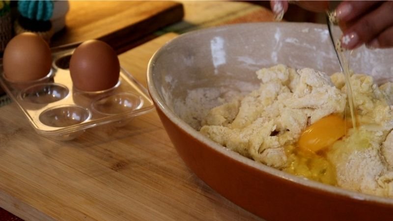 Agregando huevos uno a uno a la masa templada para mi receta de pão de queijo tradicional.