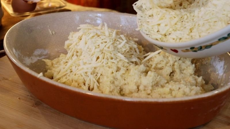 Agregando el queso rallado a la masa para mi receta de pão de queijo tradicional.
