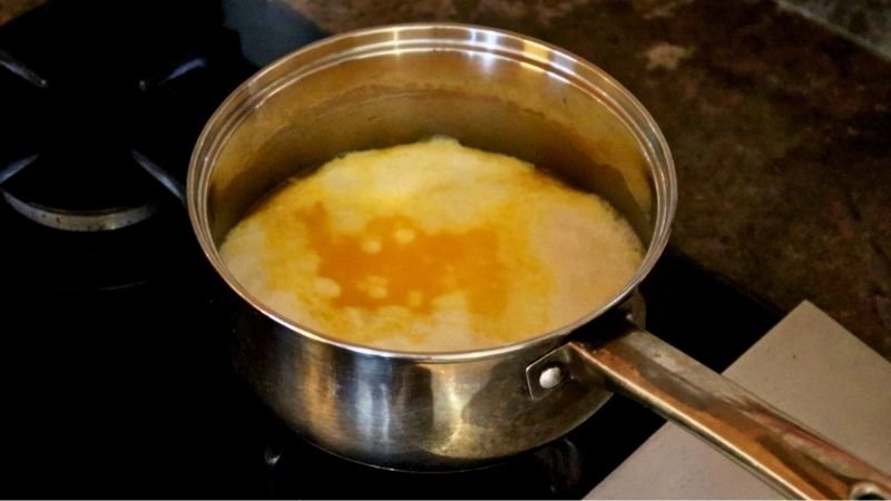 Olla en la estufa calentando líquidos para el escaldado del pão de queijo tradicional.