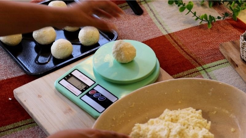 Pesando las porciones de masa en una báscula digital para mi receta de pão de queijo tradicional.